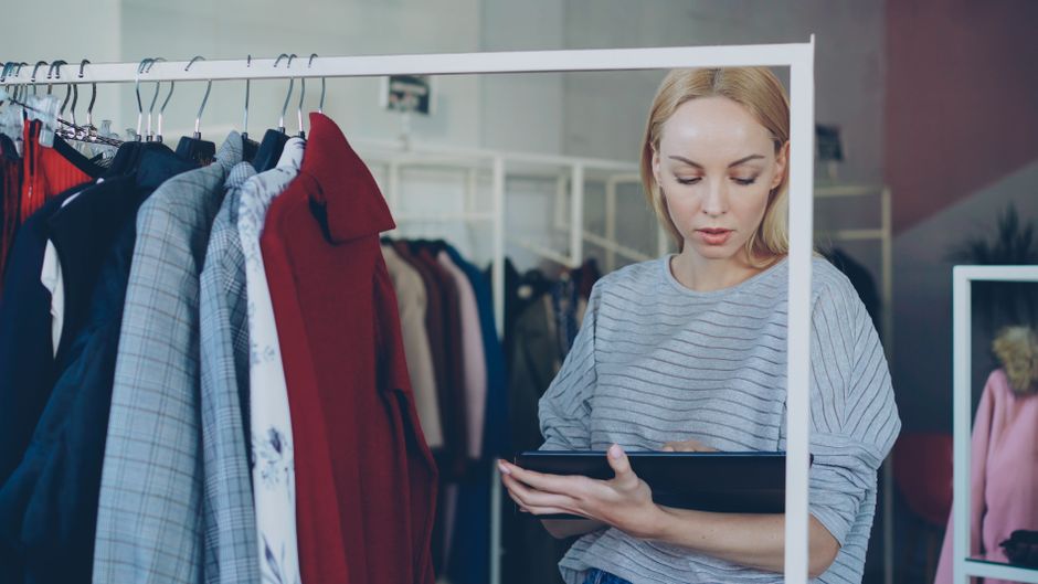 Chủ shop thời trang đang kiểm tra đơn hàng trên máy tính bảng và điện thoại thông minh